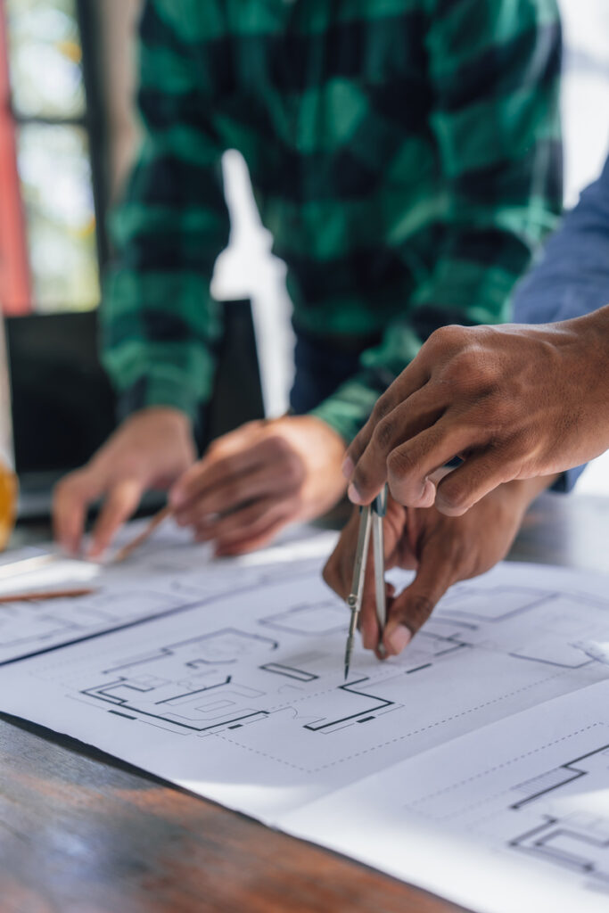 Engineers consulting team close up to design building blueprints paper for clients with building models to work at office.